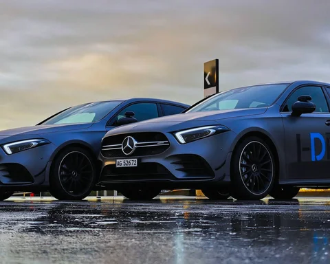 Zwei Fahrschulfahrzeuge von I-Drive auf nassem Asphalt