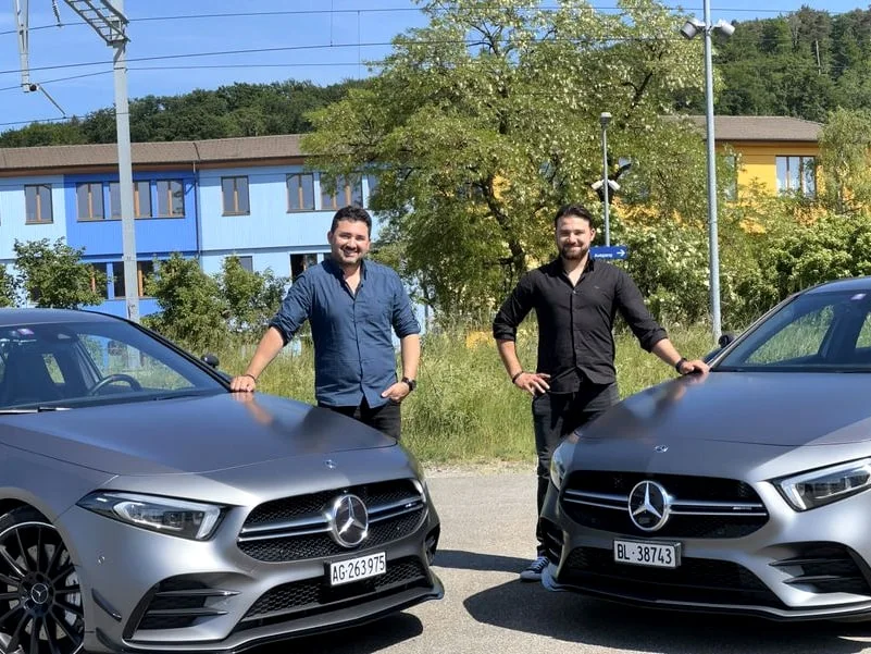 Die Fahrlehrer Erhan und Orhan Oeztürk zwischen ihren Ausbildungsfahrzeugen